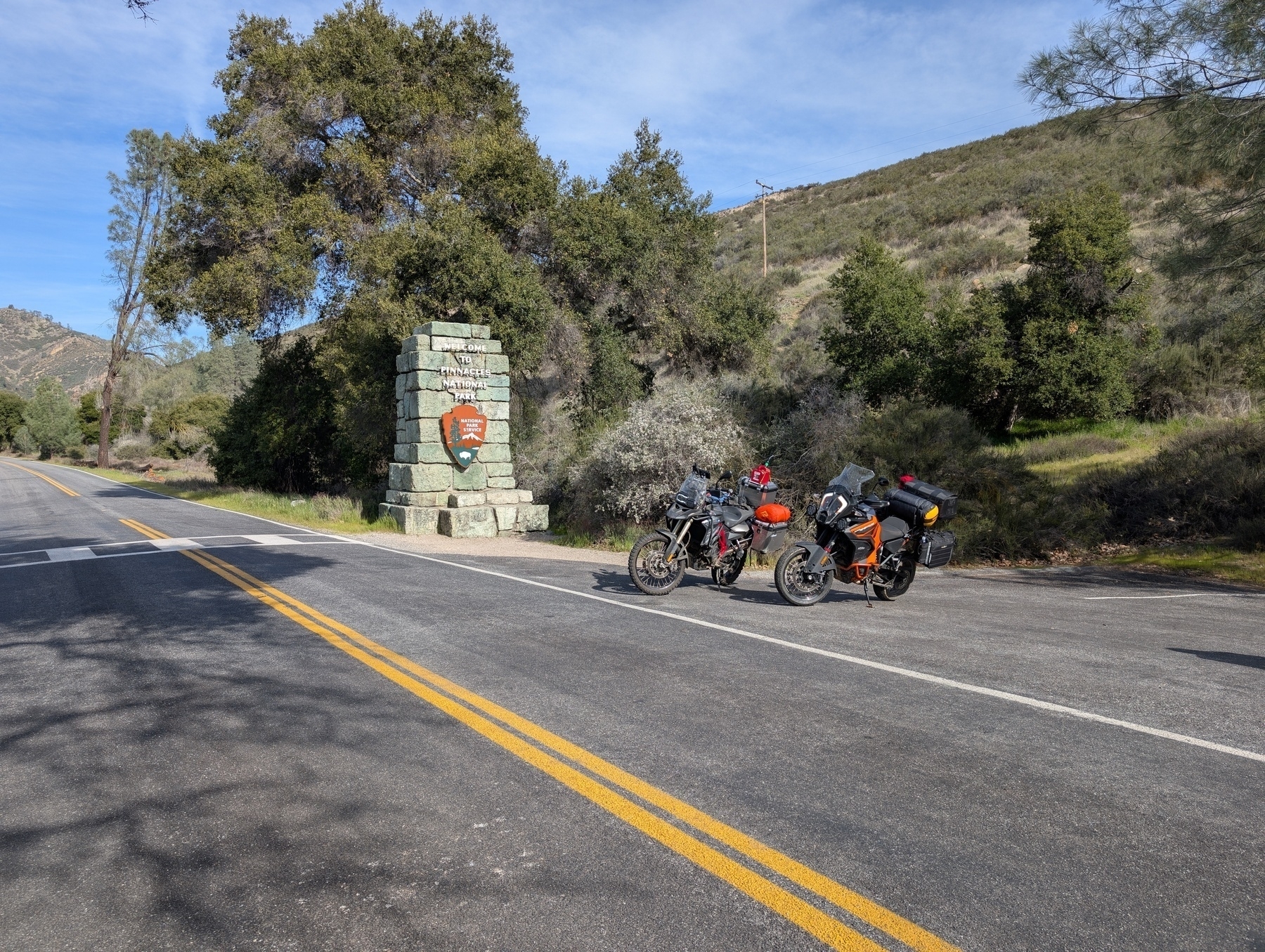 An F800GS and KTM SuperAdventure motorcycle parked in front of the pinnacles national monument sign