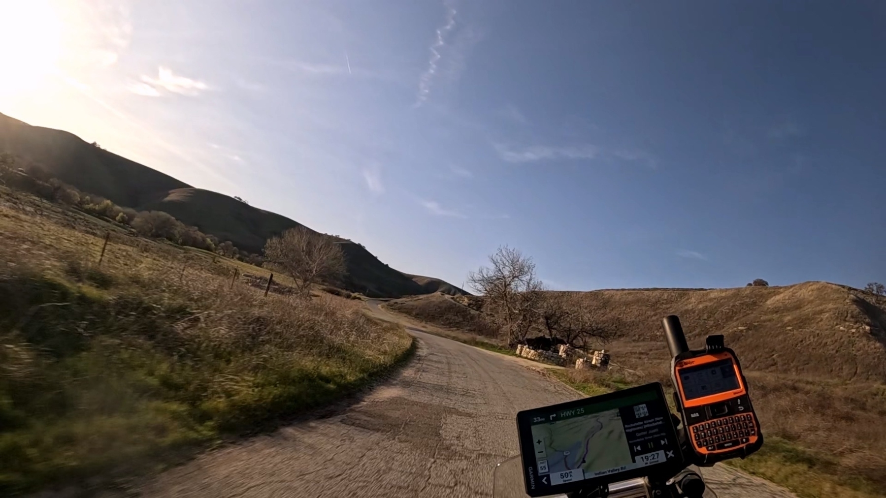 A narrow, cracked and winding road passes by the ruins of a stone farm building. A GPS is visible in the foreground.