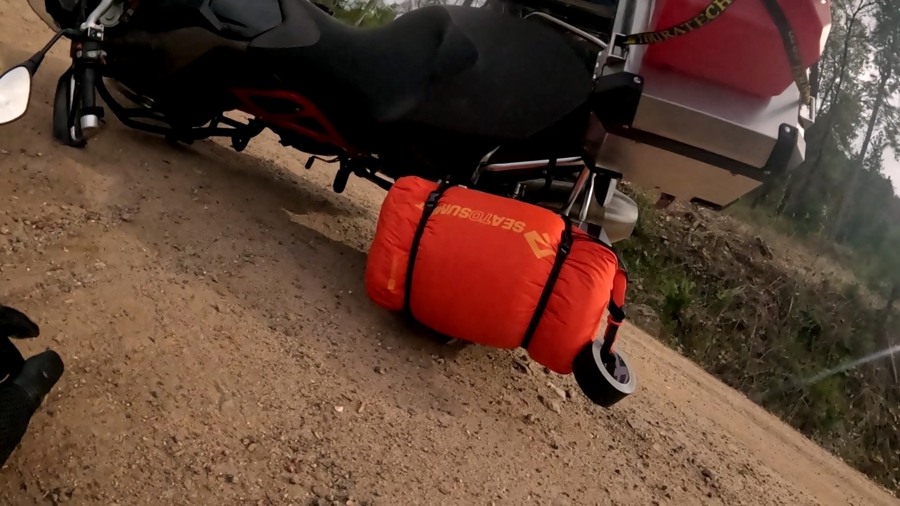A motorcycle, laying on its side on a very slick, rocky dirt road.