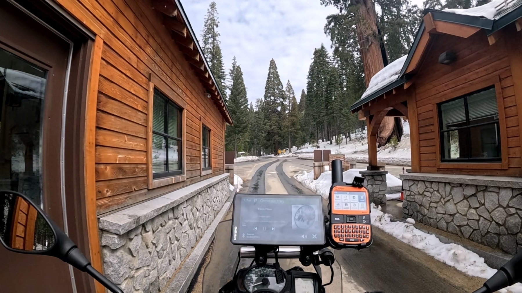 A motorcycle is parked at a snowy mountain road entrance to kings canyon.
