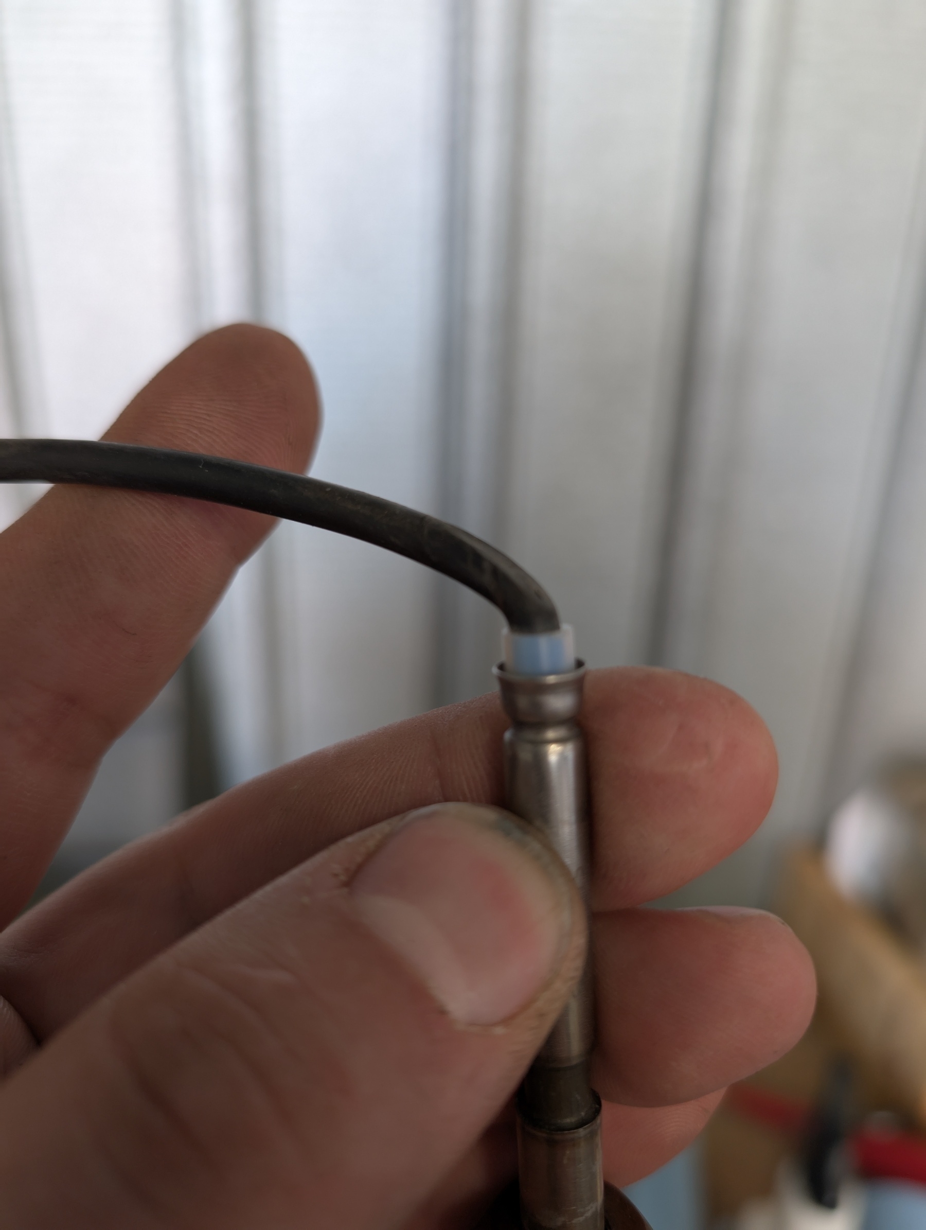 Auto-generated description: A person is holding a small metallic connector attached to a black cable.